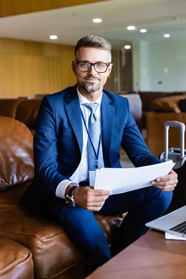 handsome businessman in formal wear and glasses holding documents e1714642288993